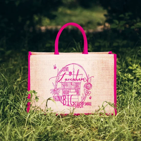 bag with a set for a summer picnic. straw bag with wine bottle, glasses and ass pillows. bag with picnic items on the lawn in the lilac garden.